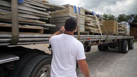 Over-the-shoulder-slo-mo-of-trucker-checking-load-on-tractor-trailer