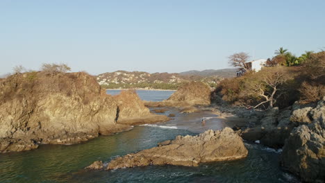 toma aérea que pasa sobre una playa rocosa para revelar un pequeño pueblo costero