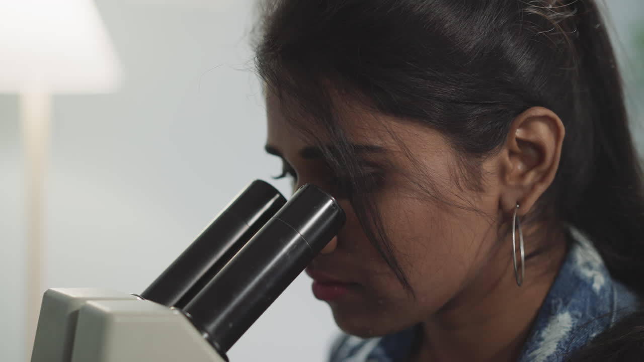 Una donna osserva nuovi tipi di batteri al microscopio.