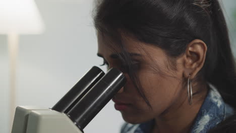 mujer mira nuevos tipos de bacterias a través del microscopio