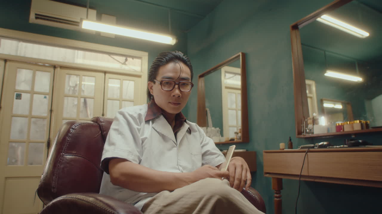 Asian Man Combing Hair Posing for Camera in Barbershop