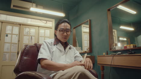 asian man combing hair posing for camera in barbershop
