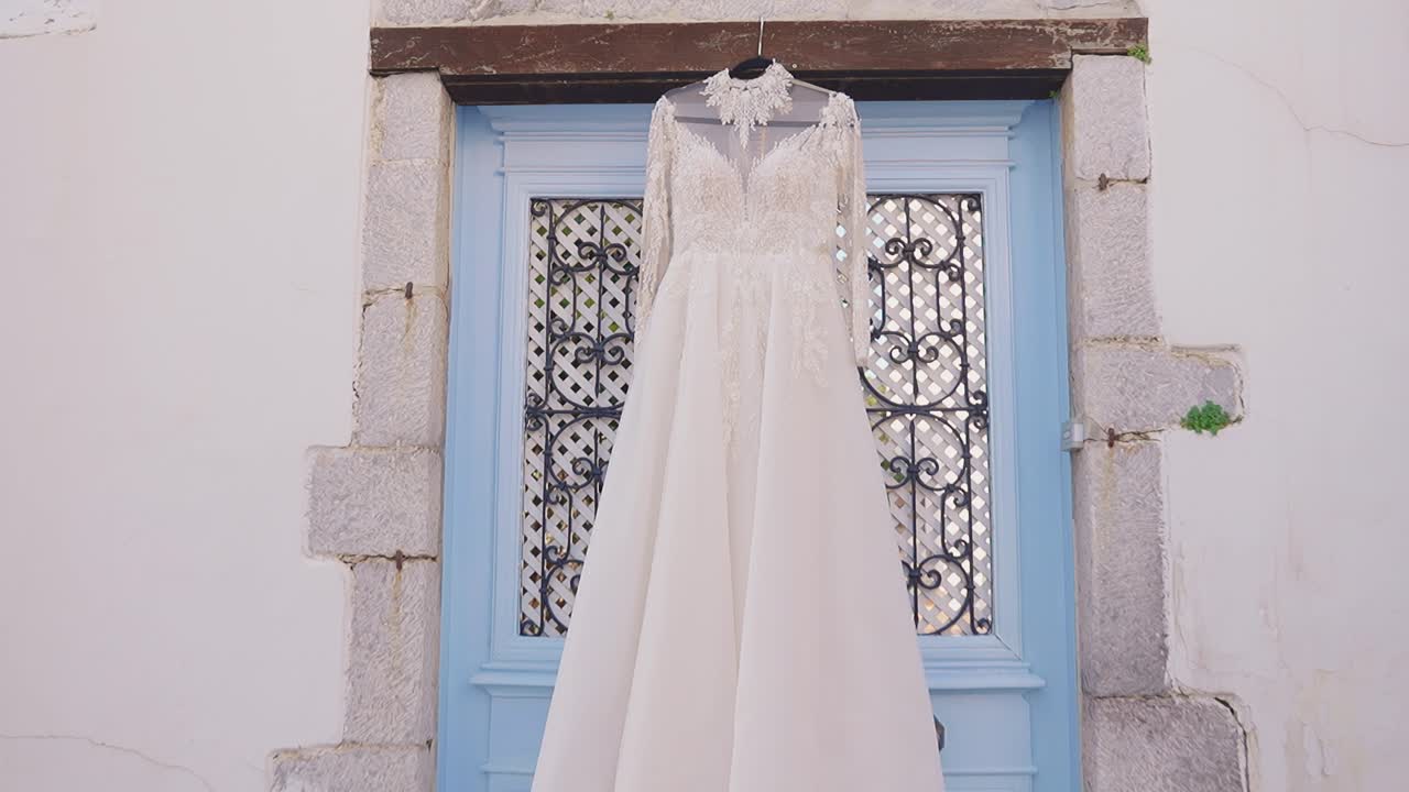 L'abito da sposa è appeso a una porta blu rustica, emanando eleganza e fascino.