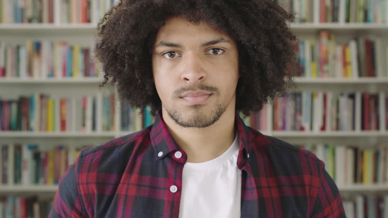 retrato de un joven estudiante sonriendo estantería biblioteca universidad