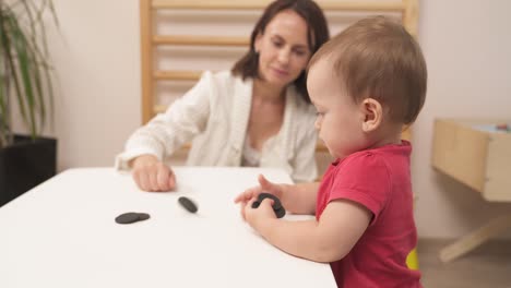 especialista en girar juguetes redondos en la mesa. bonita niña bebé tratando de hacer lo mismo. desarrollo de los niños habilidades motoras finas, imaginación y pensamiento lógico.