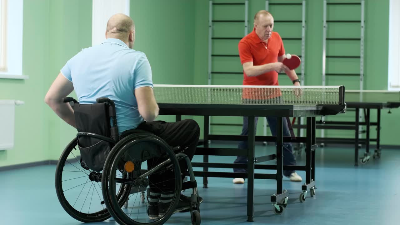 체어에 앉아 있는 남자가 핑핑을 하고, 장애인들이 탁구를 하고, 장애인의 재활, 스포츠.