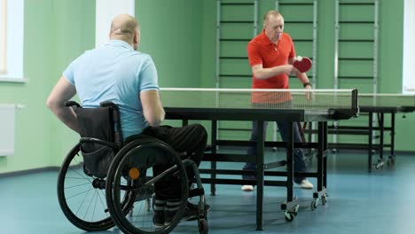 a man in a wheelchair plays ping pong. people with disabilities play table tennis. rehabilitation of the disabled. sport.