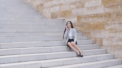 Happy-executive-with-phone-and-seated-on-stairs