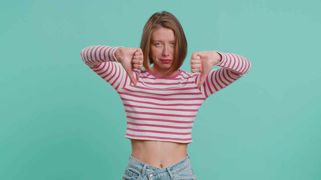 Upset attractive young woman girl showing thumbs down sign gesture disapproval dissatisfied dislike