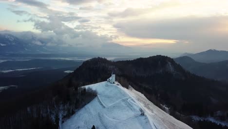 Vista-De-La-Iglesia-Jamnik-En-Un-Paisaje-Invernal-Con-Un-Colorido-Amanecer-En-Kranj,-Eslovenia