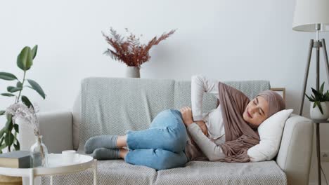 woman experiencing stomach pain on couch