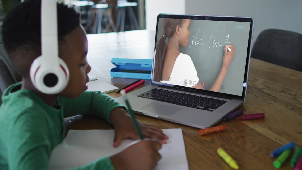 African american boy sitting at desk using laptop having online school lesson