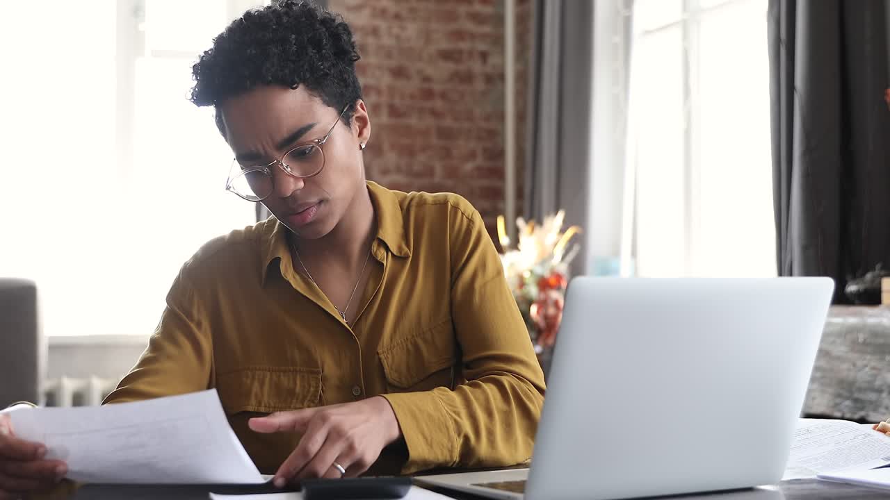 African woman reviewing bills, manage personal finances, feels stressed