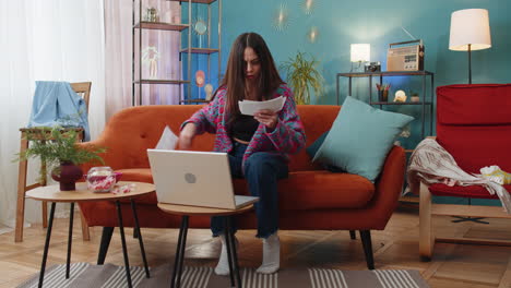 stressed young woman looking at unpaid bank debt loan doing paperwork planning budget throws bills