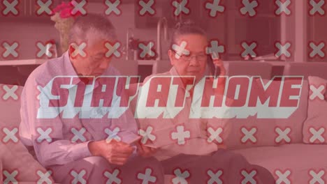 animación de palabras quedarse en casa con cruces moviéndose sobre una pareja asiática mayor usando desarrollo tecnológico