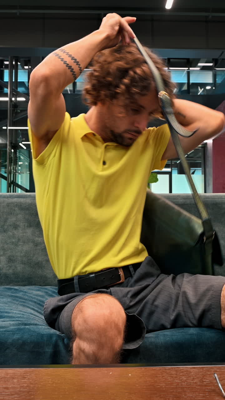 Man in yellow shirt packing up his things and going home from work. Vertical