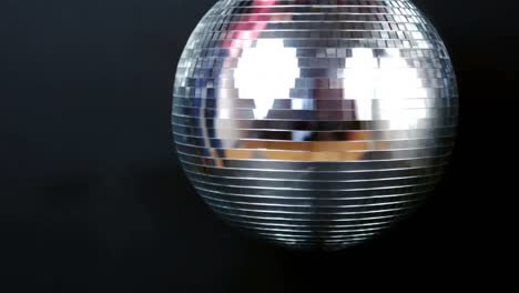 digital animation of grey paper burning over silver spinning disco ball against black background