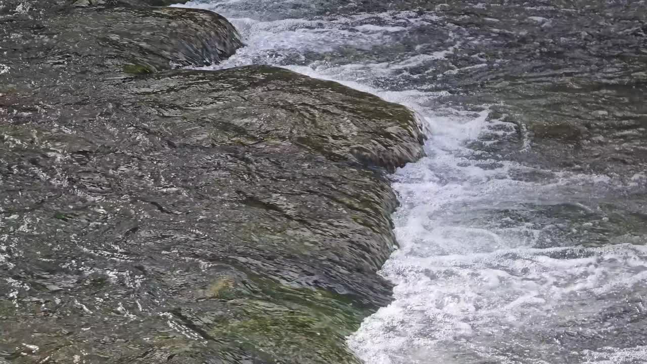 Dinamiche dell'acqua: forte corrente e spruzzi in un letto di fiume naturale