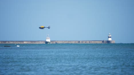 coast guard helicopter rescue winch training with trawler boat at holyhead breakwater lighthouse