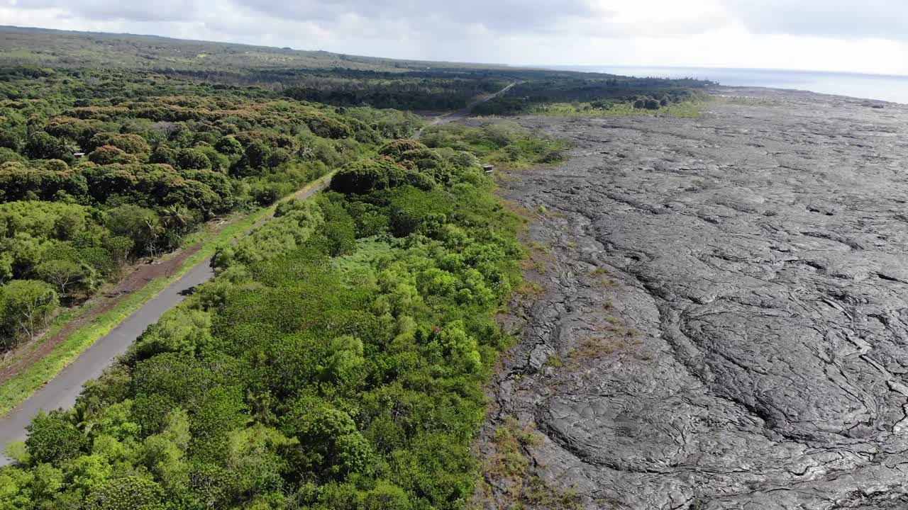 volando sobre flujos volcánicos junto a la selva de hawai con una carretera que corre paralela