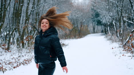 Life joy and happiness. Long-haired smiling brunette jumping and turning in the park in winter.