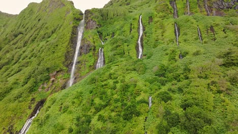 volando hacia la fila de cascadas poço ribeira do ferreiro en la isla de flores, aérea