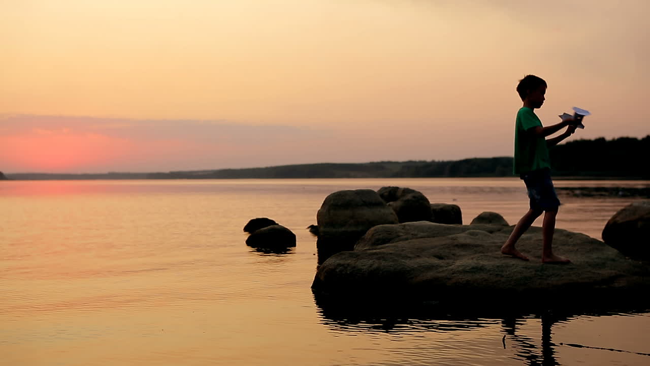 Boy Playing On Stony Beach. Young boy actively playing on stony beach at sunset