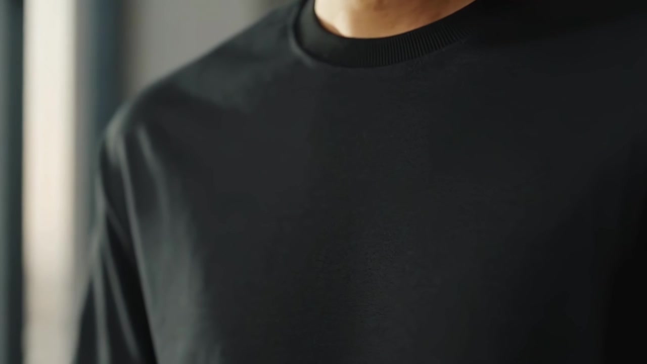 Junger Mann posiert in schwarzem T-Shirt in moderner Stadtwohnung