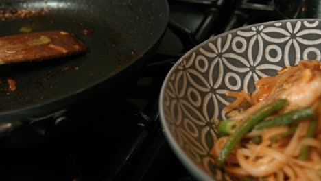 empty pan next to plated king prawn pad thai