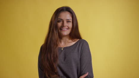 head and shoulders studio portrait of smiling woman against yellow background 2