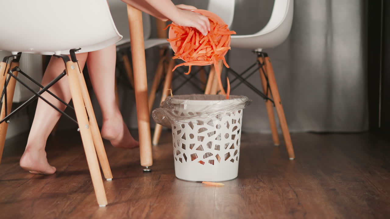 Child discarding food waste in a kitchen