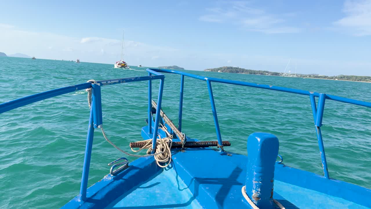 A serene boat ride over turquoise waters in Chalong Bay, Phuket, with clear skies and distant islands