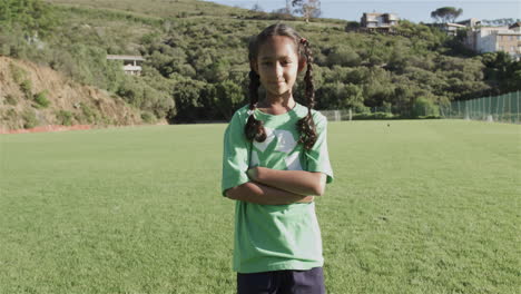 biracial girl stands confidently on a soccer field wearing a green recycling t-shirt