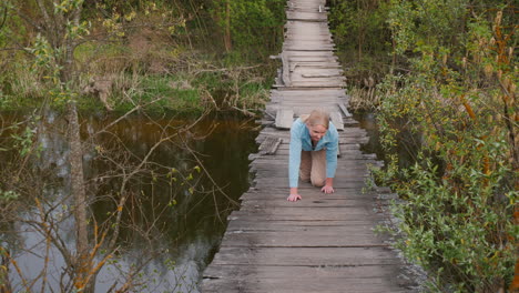 woman crossing a damaged wooden bridge over a river