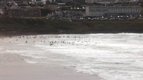 hand-held shot of a large crowd of surfers trying to catch waves at fistral beach