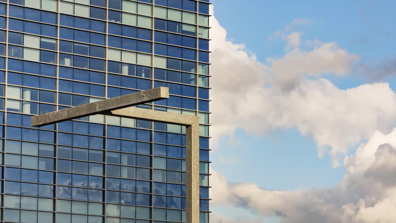Glass facade with modern street lantern reflecting moving clouds and shifting sunlight shadows