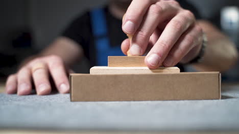 worker in overalls labeling a cardboard package with a wooden stamp