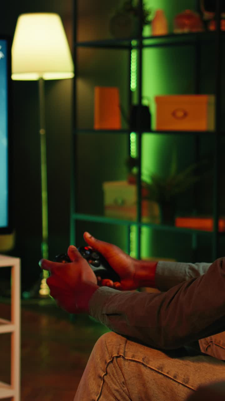 Video verticale di un uomo in un home theatre che utilizza un gamepad per console di gioco high-tech