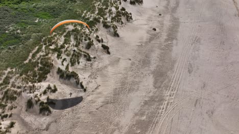 parapente navegando sobre dunas de arena de playa holandesa proyectando sombras