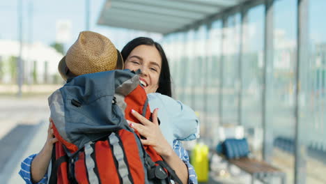 Rear-view-of-caucasian-man-meeting-and-hugging-a-caucasian-woman-traveller-friend-at-train-station