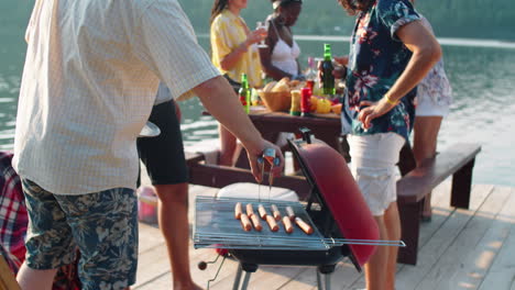 men cooking bbq sausages and having beer on outdoor party