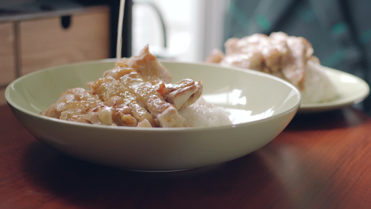 Pouring White Sauce On Fried Chicken Topped On Rice In A Plate - closeup shot