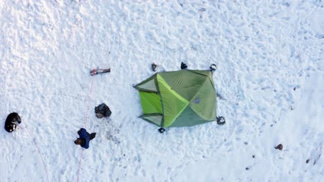 camper walking towards his alaskan malamute dog lying on snowy ground at winter