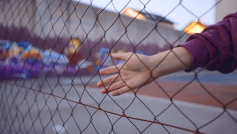 A-tennis-player-running-her-hand-along-size-a-wired-fence-at-a-tennis-court