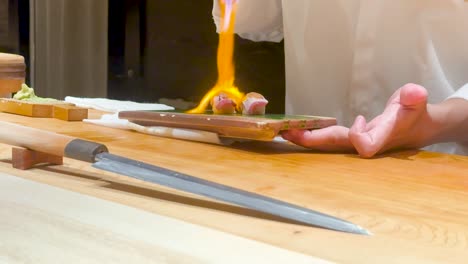 el chef usa la llama para preparar el plato de sushi.