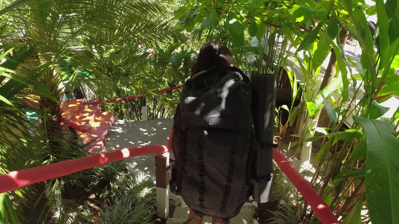 젊은 라티나 배 ⁇ 여행자가 열대 정글에서 숙소 계단을 내려  ⁇ 고 있습니다.