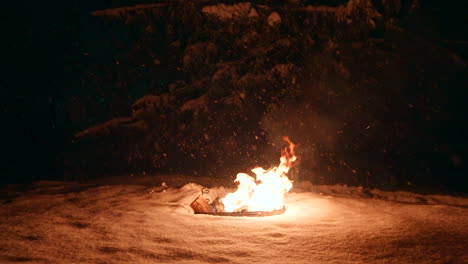 llamas calientes se elevan de fuego ardiente en el suelo, copos de nieve cayendo
