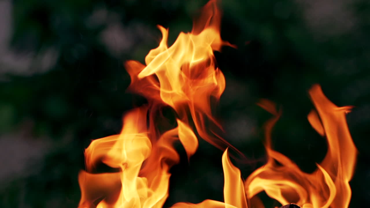 Twisting tongues of flame on dark background. Close-up of magnetic flame of outdoor shot. Slow motion.