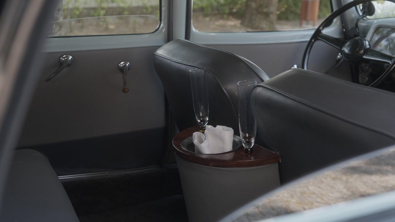 Interior view of a classic vintage car featuring leather seats and two champagne flutes