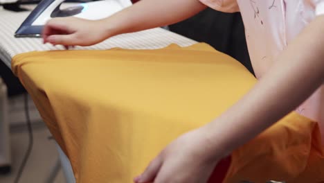 closeup of a woman ironing clothing by stream iron on board at home with slow motion scene